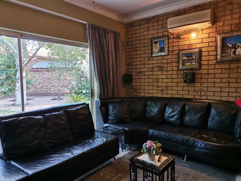 A cozy living room featuring an exposed brick feature wall, crown molding, and a large sliding glass door providing access to the garden.