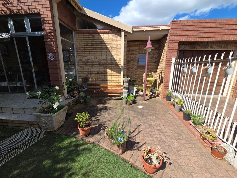 A paved rear courtyard area featuring face brick walls, a metal security fence, and access to the home via a sliding glass door.