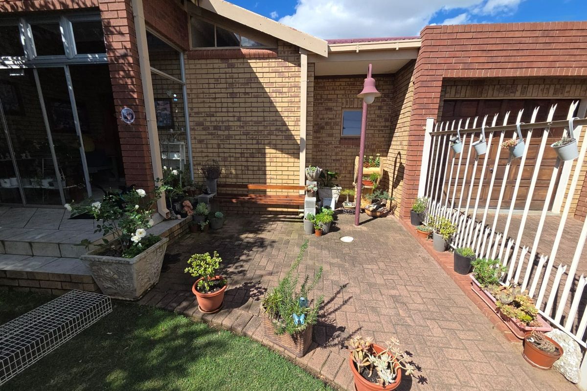 A paved rear courtyard area featuring face brick walls, a metal security fence, and access to the home via a sliding glass door.