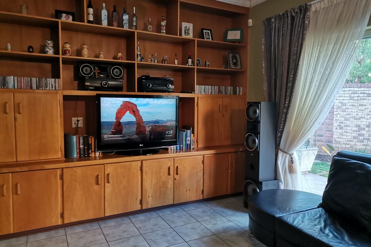 Living room featuring extensive built-in wooden cabinetry, tiled flooring, and access to the patio through a sliding glass door.