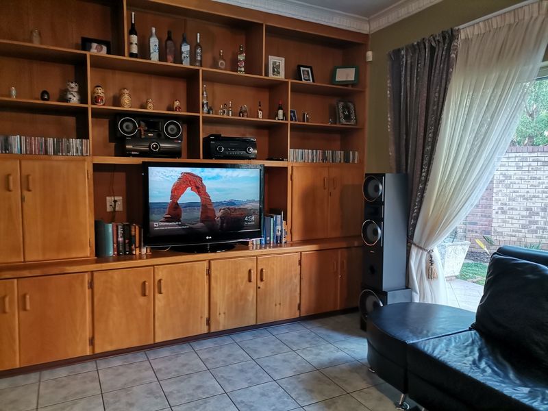 Living room featuring extensive built-in wooden cabinetry, tiled flooring, and access to the patio through a sliding glass door.