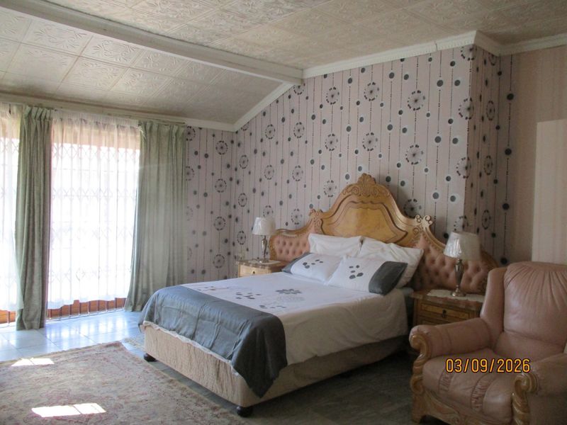 Spacious bedroom featuring patterned wallpaper, a decorative pressed metal ceiling, and sliding glass doors providing access to the exterior.