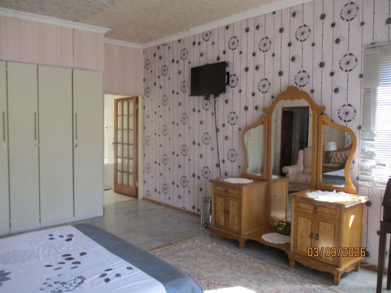 A bedroom featuring built-in wardrobes, patterned wallpaper, and a french door leading to an adjacent room.