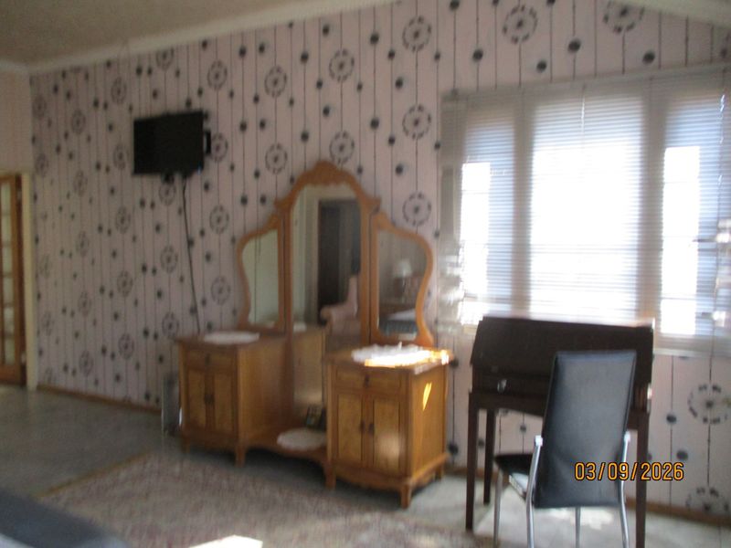 A bedroom featuring patterned wallpaper and venetian blinds on the window.