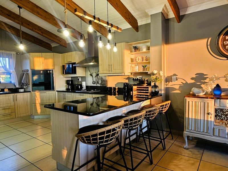 A well-appointed kitchen featuring exposed timber ceiling beams, granite countertops, a central island, and built-in cabinetry with integrated appliances.