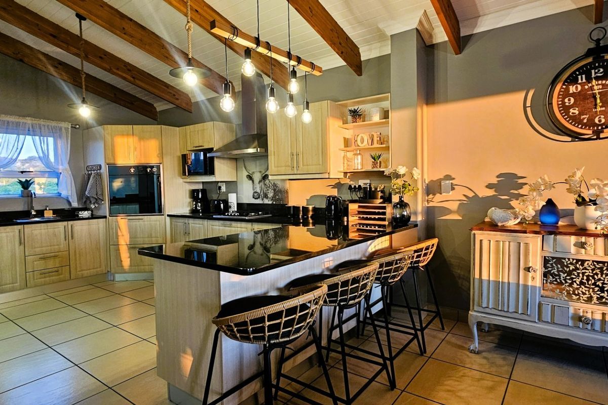 A well-appointed kitchen featuring exposed timber ceiling beams, granite countertops, a central island, and built-in cabinetry with integrated appliances.