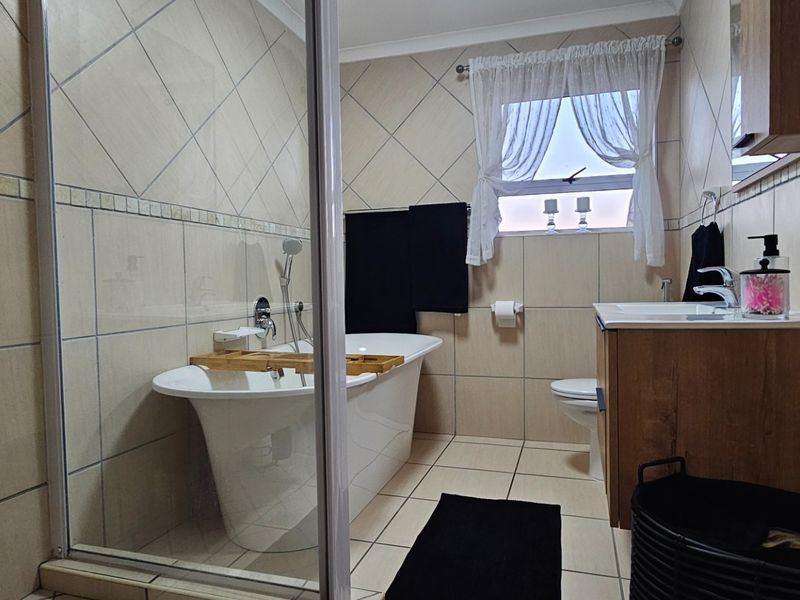 A well-maintained bathroom featuring a freestanding bathtub, a separate shower enclosure, and a modern vanity cabinet with neutral wall and floor tiling.