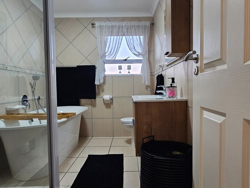 A well-maintained bathroom featuring a freestanding bathtub, a separate shower enclosure, and a wooden vanity cabinet with tiled finishes.
