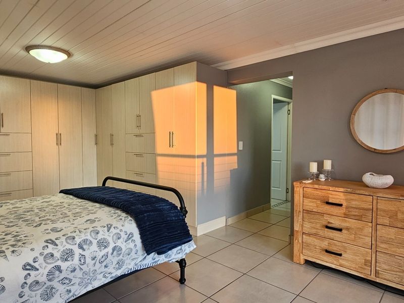 A well-maintained bedroom featuring extensive built-in cabinetry, tiled flooring, and a classic tongue and groove ceiling.
