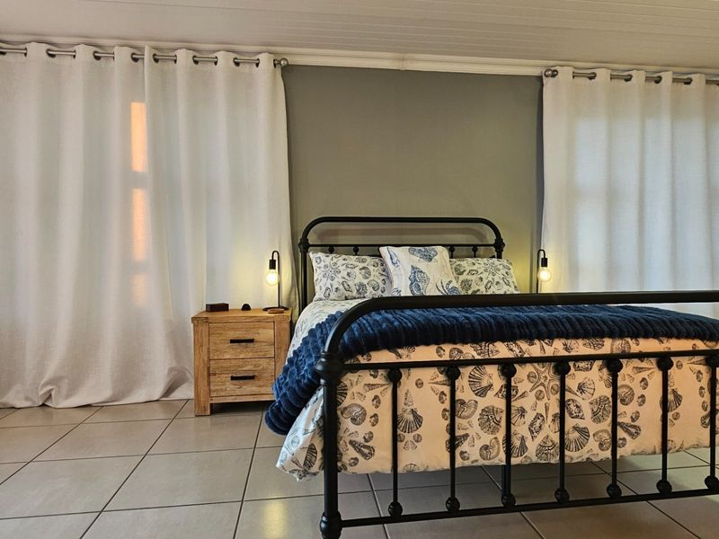 A well-maintained bedroom featuring tiled flooring, a built-in wardrobe, and a classic tongue and groove ceiling, offering a clean and functional living space.