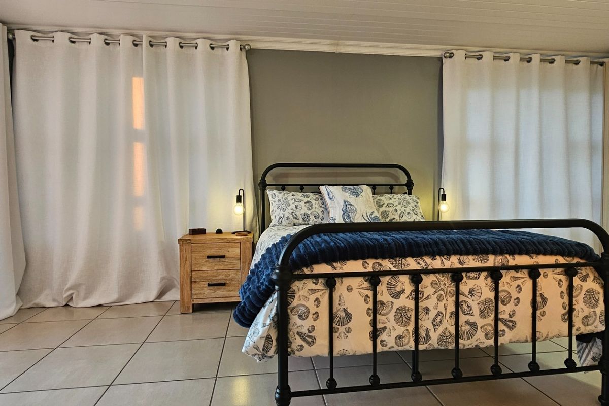 A well-maintained bedroom featuring tiled flooring, a built-in wardrobe, and a classic tongue and groove ceiling, offering a clean and functional living space.