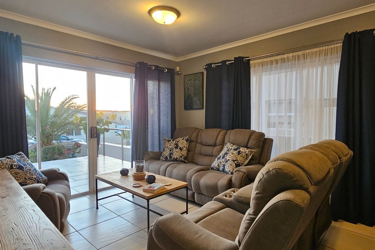 A comfortable living room featuring tiled flooring and large sliding glass doors that provide access to an outdoor patio area.