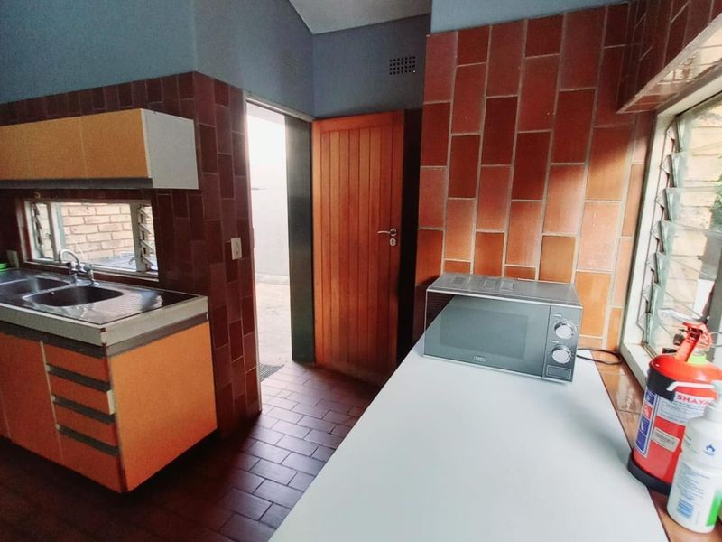 A functional scullery area featuring built-in cabinetry, a stainless steel sink, and tiled finishes, providing a practical secondary workspace.