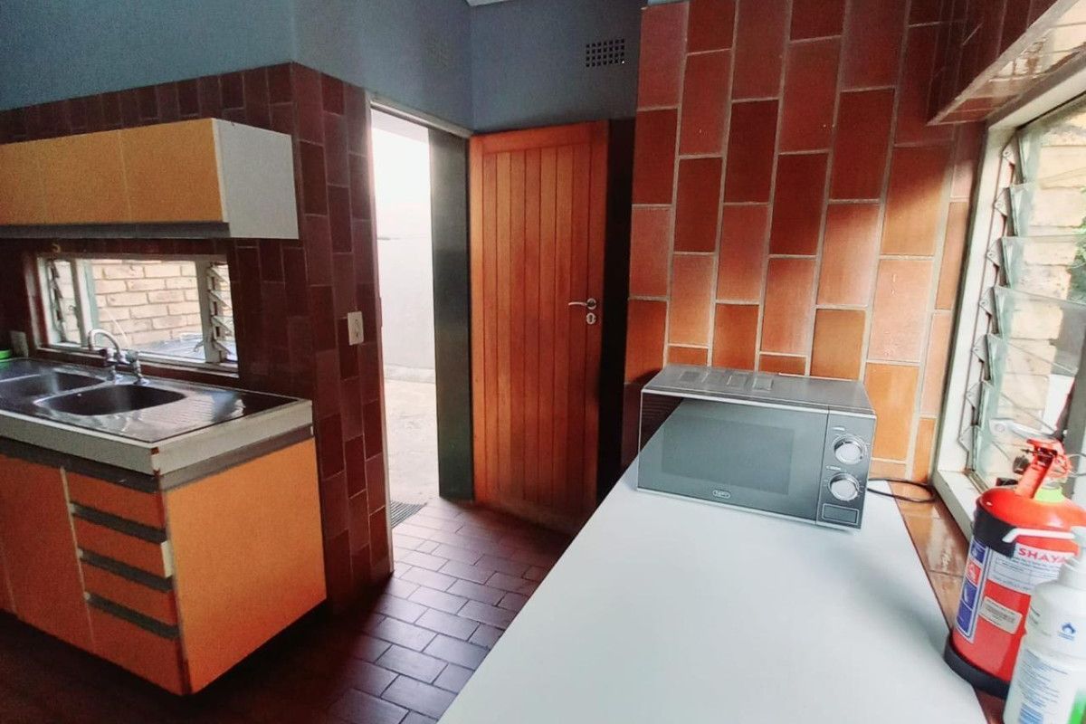 A functional scullery area featuring built-in cabinetry, a stainless steel sink, and tiled finishes, providing a practical secondary workspace.