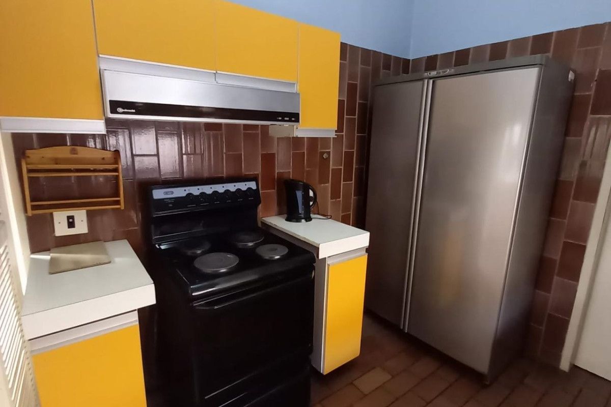A functional kitchen featuring yellow cabinetry, a tiled backsplash, and tiled flooring, offering a dated aesthetic ready for modernization.