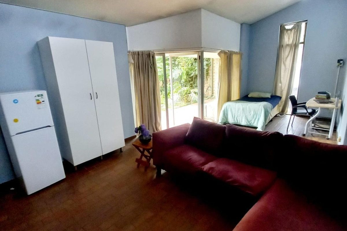 Open plan living area featuring vaulted ceilings, track lighting, and sliding glass doors providing access to the garden.