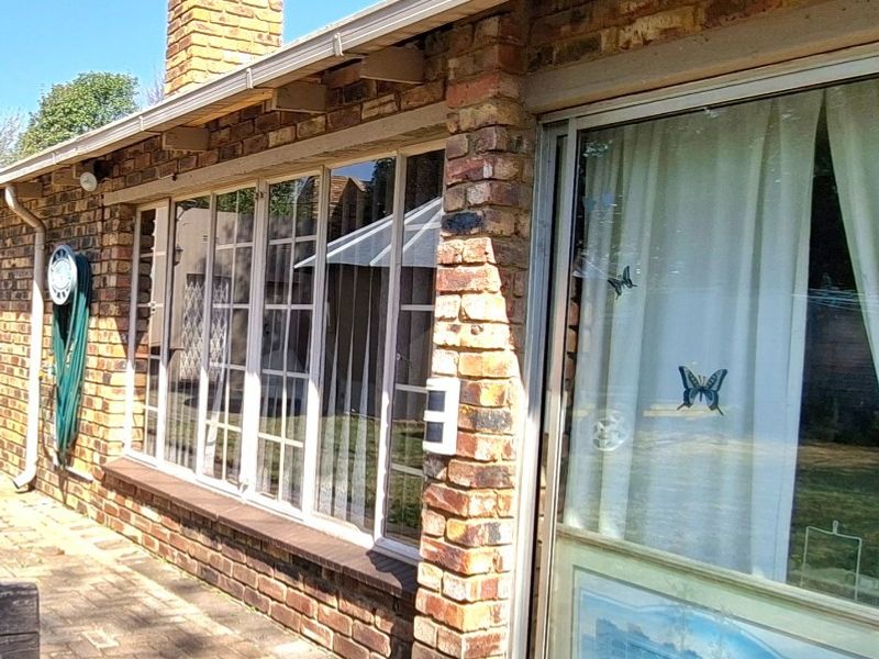 Rear exterior view of the house featuring face-brick walls, paved patio area, and large sliding glass doors.