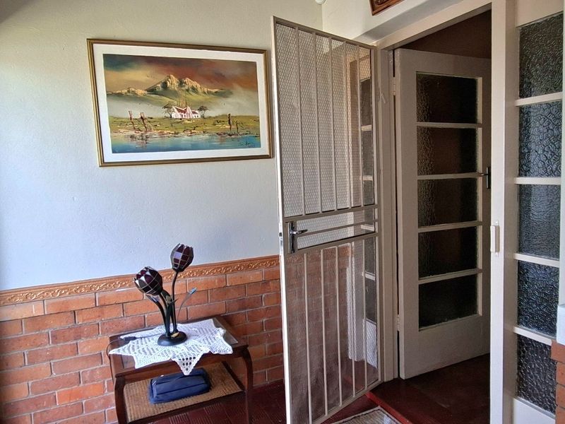 Entrance area featuring a security gate, brick wainscoting, and glass panelled doors leading into the home.