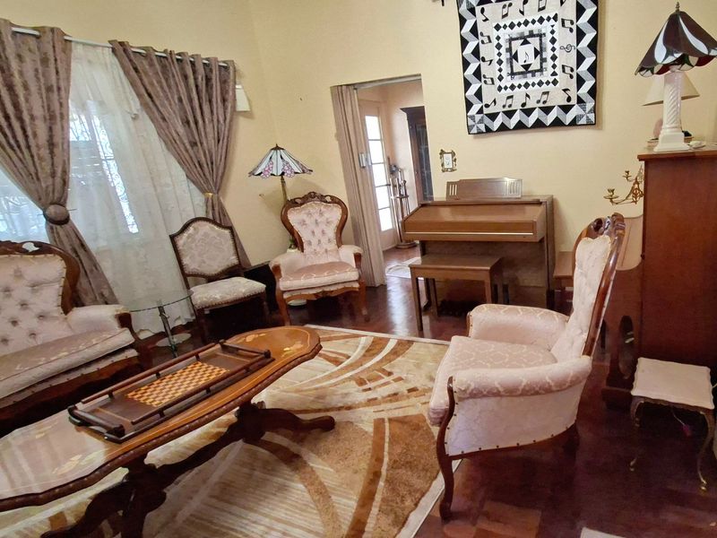 A traditional living room featuring classic parquet flooring and a doorway leading to an adjacent space, offering a warm and established atmosphere.