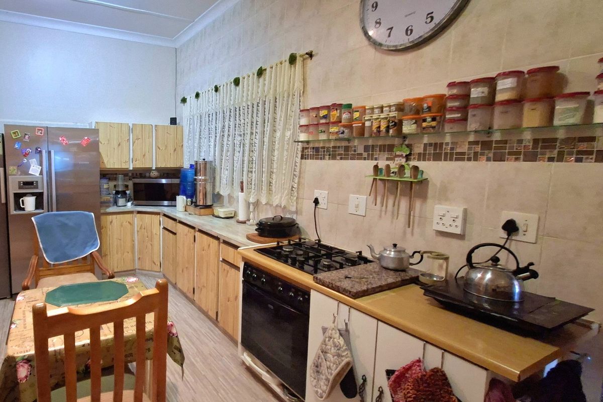 A functional kitchen featuring wooden cabinetry, a gas hob with electric oven, and tiled backsplash, offering a practical layout for daily cooking.