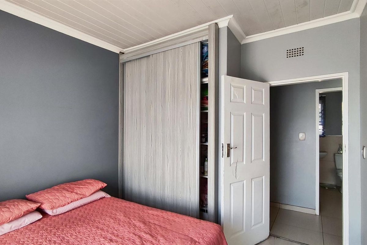Bedroom featuring a built-in sliding door wardrobe, timber panel ceiling, and direct access to an adjoining bathroom.