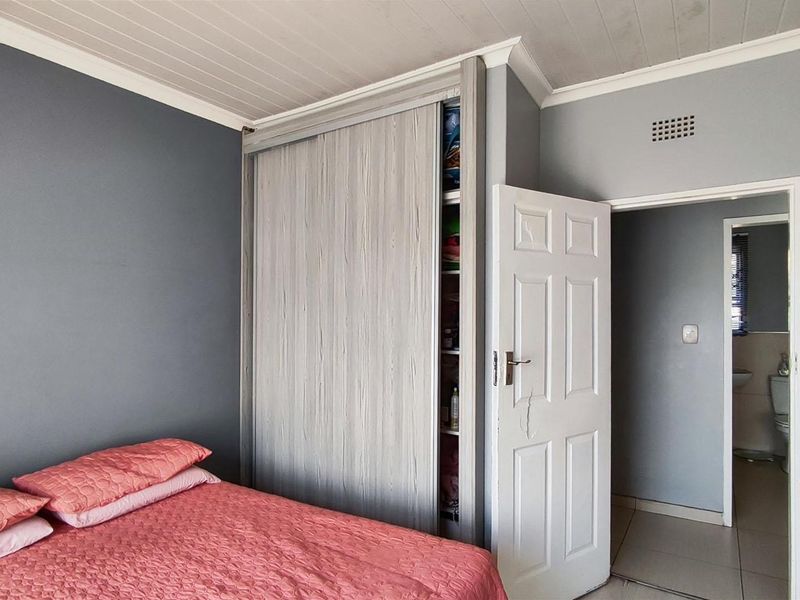 Bedroom featuring a built-in sliding door wardrobe, timber panel ceiling, and direct access to an adjoining bathroom.