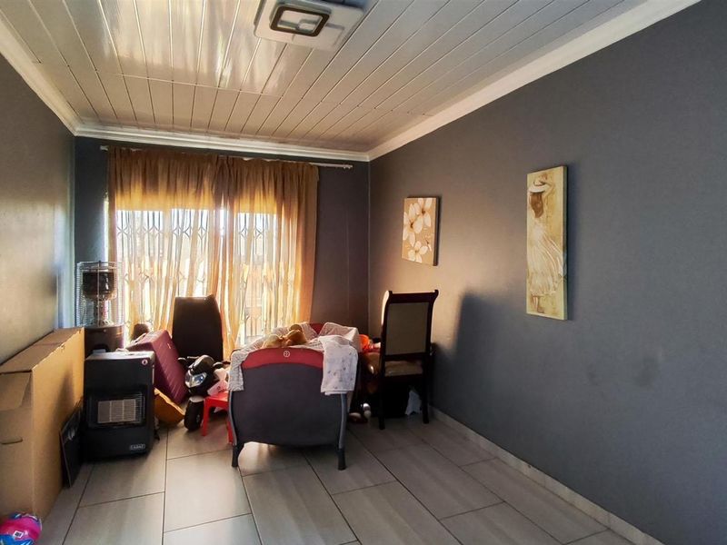 A living room featuring tiled flooring, a tongue and groove ceiling, and a sliding door with a security gate.