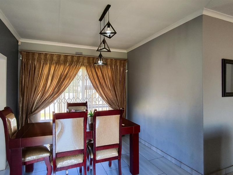 A well-maintained dining area featuring tiled flooring, modern pendant lighting, and a secure window with access to natural light.
