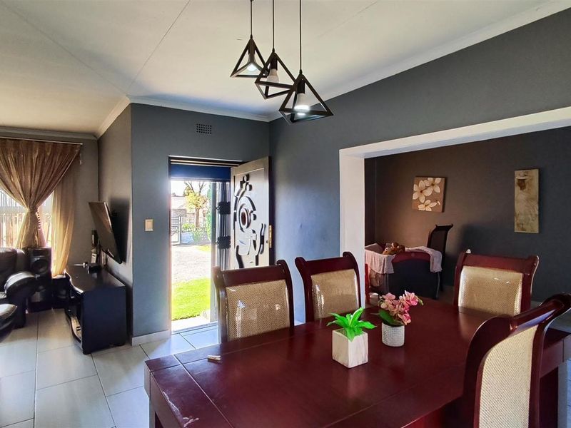 Open-plan living and dining area featuring tiled flooring, modern pendant lighting, and direct access to the exterior through a security gate.