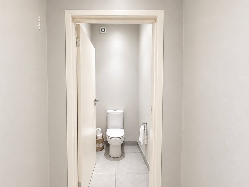 A clean and modern guest bathroom featuring a white toilet, tiled flooring, and an integrated extractor fan.