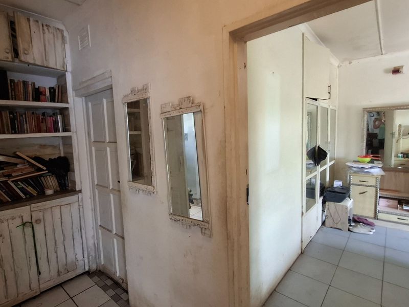 A functional hallway featuring built-in storage cabinetry and shelving, connecting multiple rooms with tiled flooring throughout.