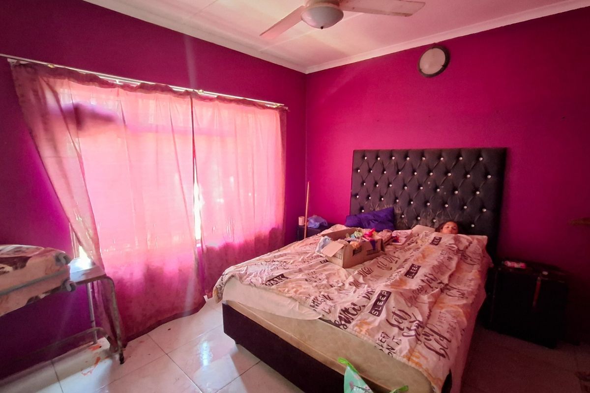 A bedroom featuring tiled flooring and a ceiling fan, currently finished with bold wall paint.