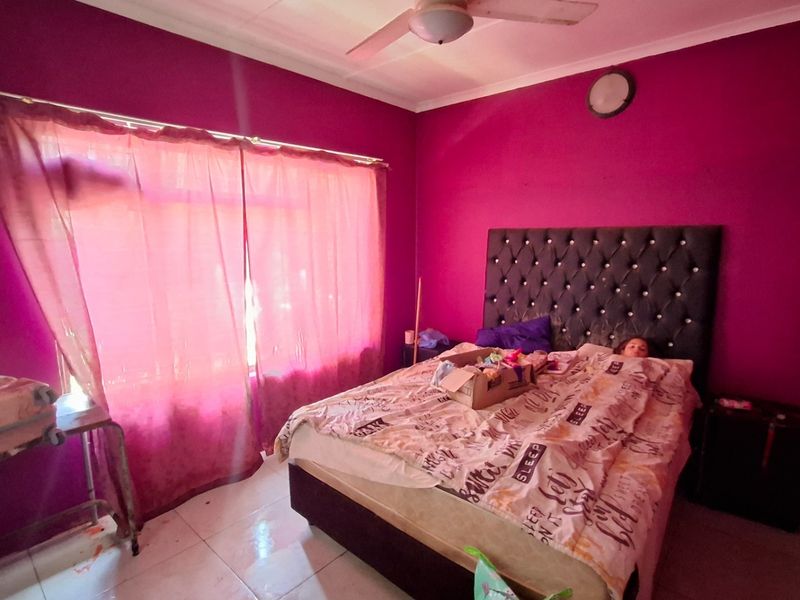 A bedroom featuring tiled flooring and a ceiling fan, currently finished with bold wall paint.