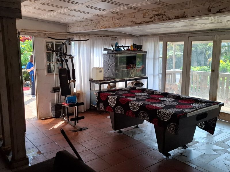 Spacious living area featuring tiled flooring, coffered ceilings, and large glass sliding doors providing access to the outdoor deck area.
