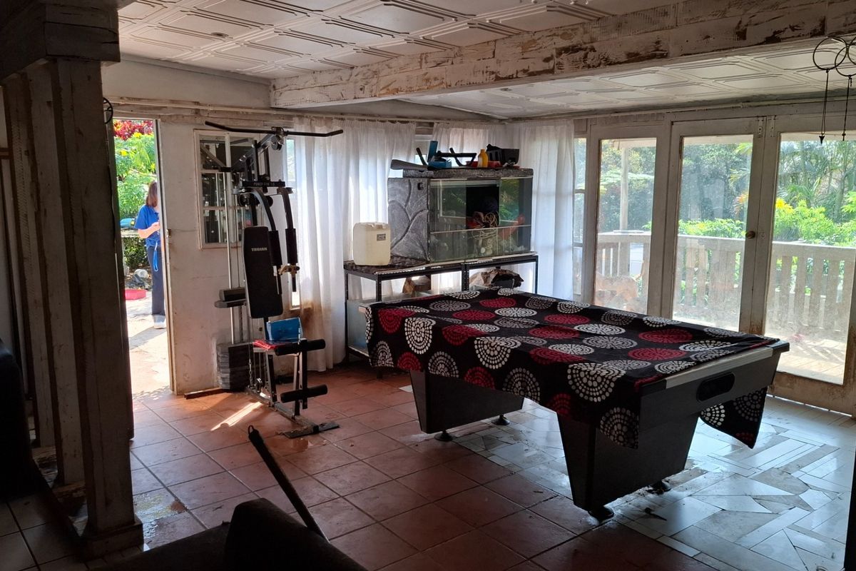 Spacious living area featuring tiled flooring, coffered ceilings, and large glass sliding doors providing access to the outdoor deck area.