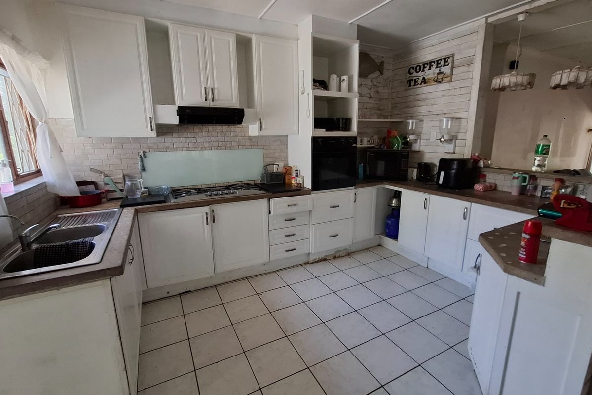 Functional kitchen featuring white cabinetry, laminate countertops, gas hob, built-in oven, and tiled flooring, offering a practical layout for daily meal preparation.
