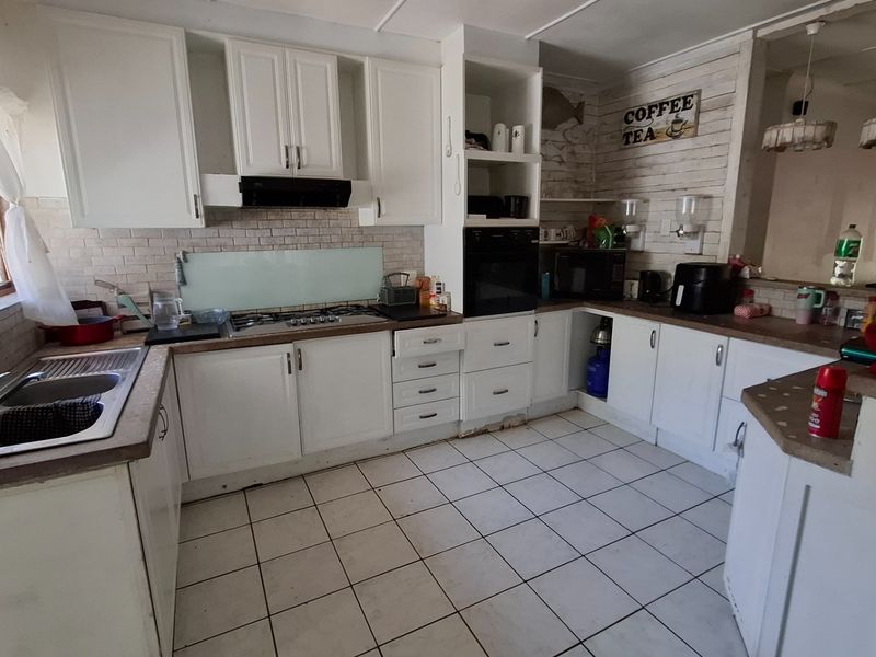 Functional kitchen featuring white cabinetry, laminate countertops, gas hob, built-in oven, and tiled flooring, offering a practical layout for daily meal preparation.