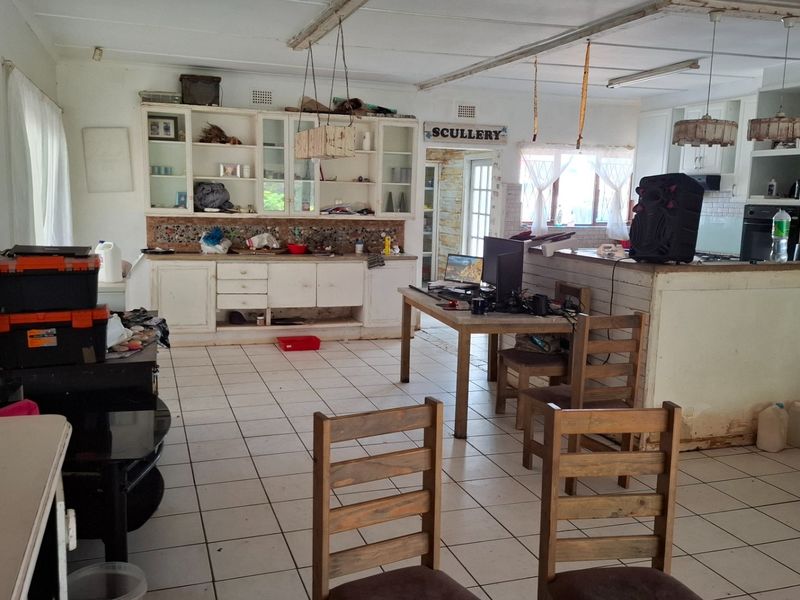 Open-plan kitchen and living area featuring tiled flooring, built-in cabinetry, and a central island, offering significant potential for modernization and renovation.