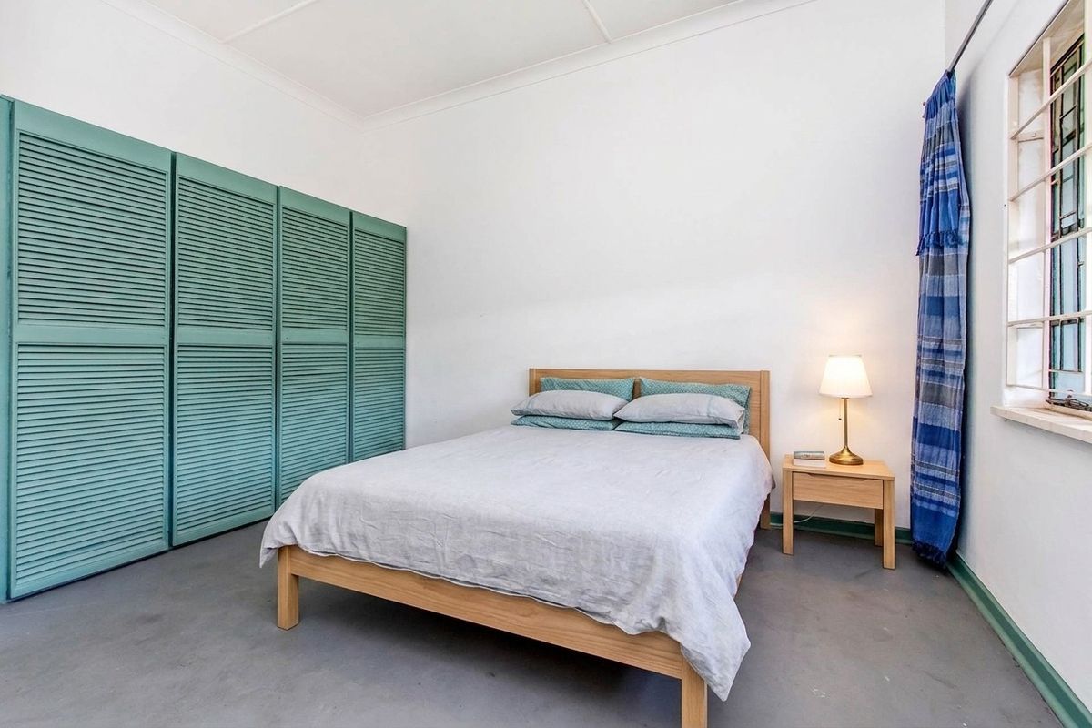 A bedroom featuring built-in cupboards with louvered doors, a window with security bars, and a coved ceiling.