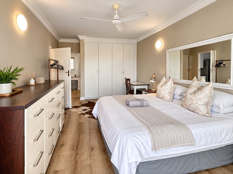 Spacious bedroom featuring built-in cupboards, laminate flooring, crown molding, and a ceiling fan, offering a comfortable and well-maintained living space.