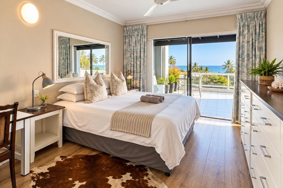 A well-maintained bedroom featuring laminate flooring, crown molding, and a sliding glass door that opens onto a balcony with ocean views.