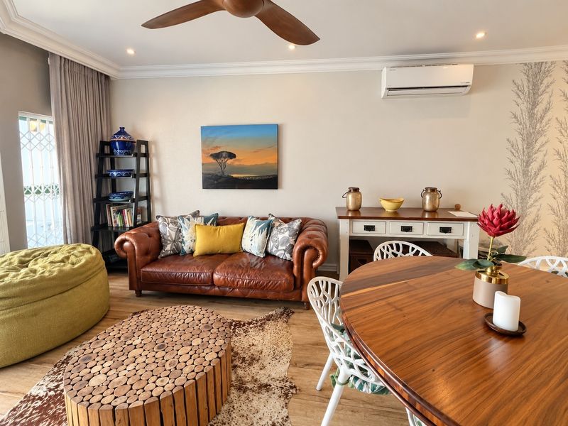 A well-maintained open-plan living and dining area featuring laminate flooring, recessed lighting, a ceiling fan, and a wall-mounted split-system air conditioner.