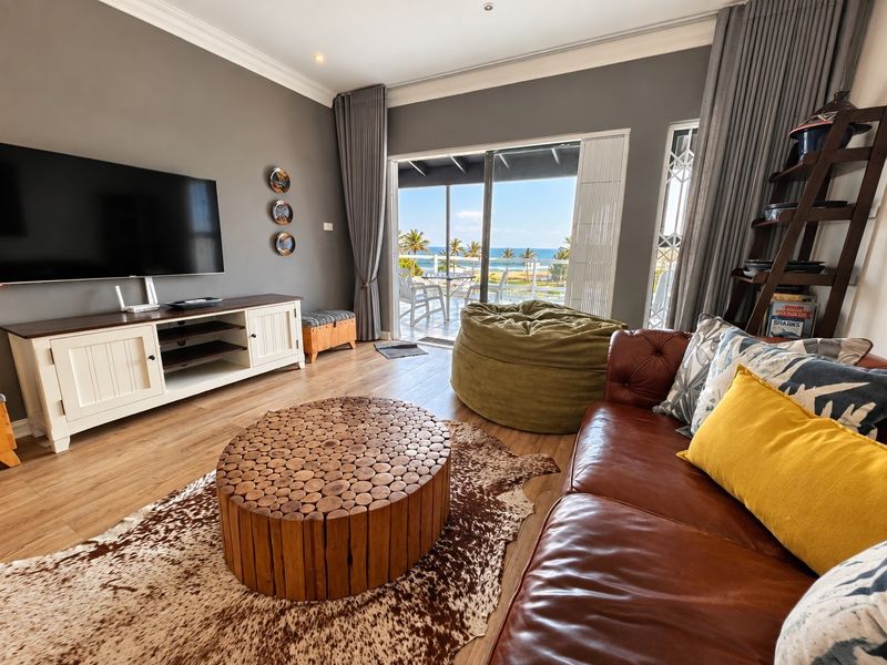 A well-maintained living room featuring laminate flooring, crown molding, and large sliding glass doors that open to a scenic ocean view.