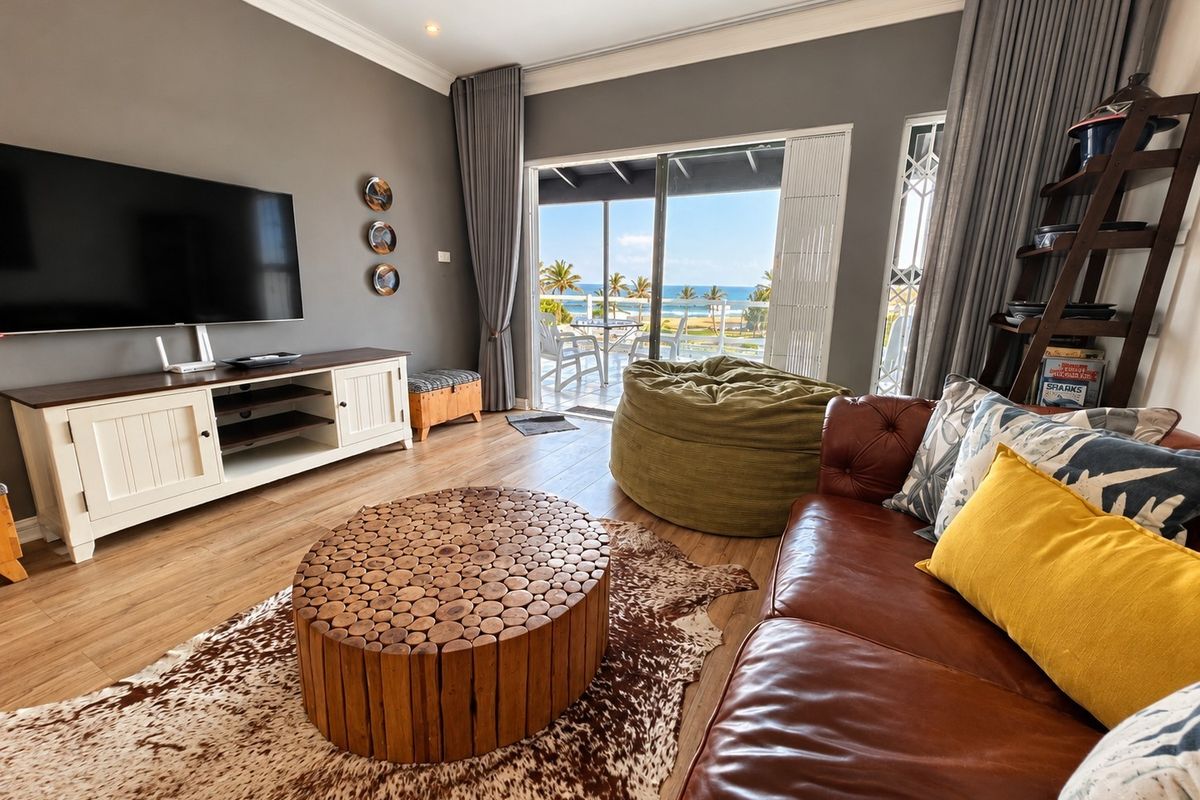 A well-maintained living room featuring laminate flooring, crown molding, and large sliding glass doors that open to a scenic ocean view.