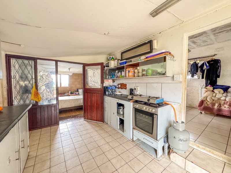 A dated kitchen area featuring tiled flooring, built-in cabinetry, and a gas stove, requiring significant maintenance and cosmetic updates.