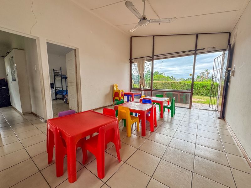 Spacious living area featuring tiled flooring, a ceiling fan, and large sliding glass doors providing direct access to the garden.