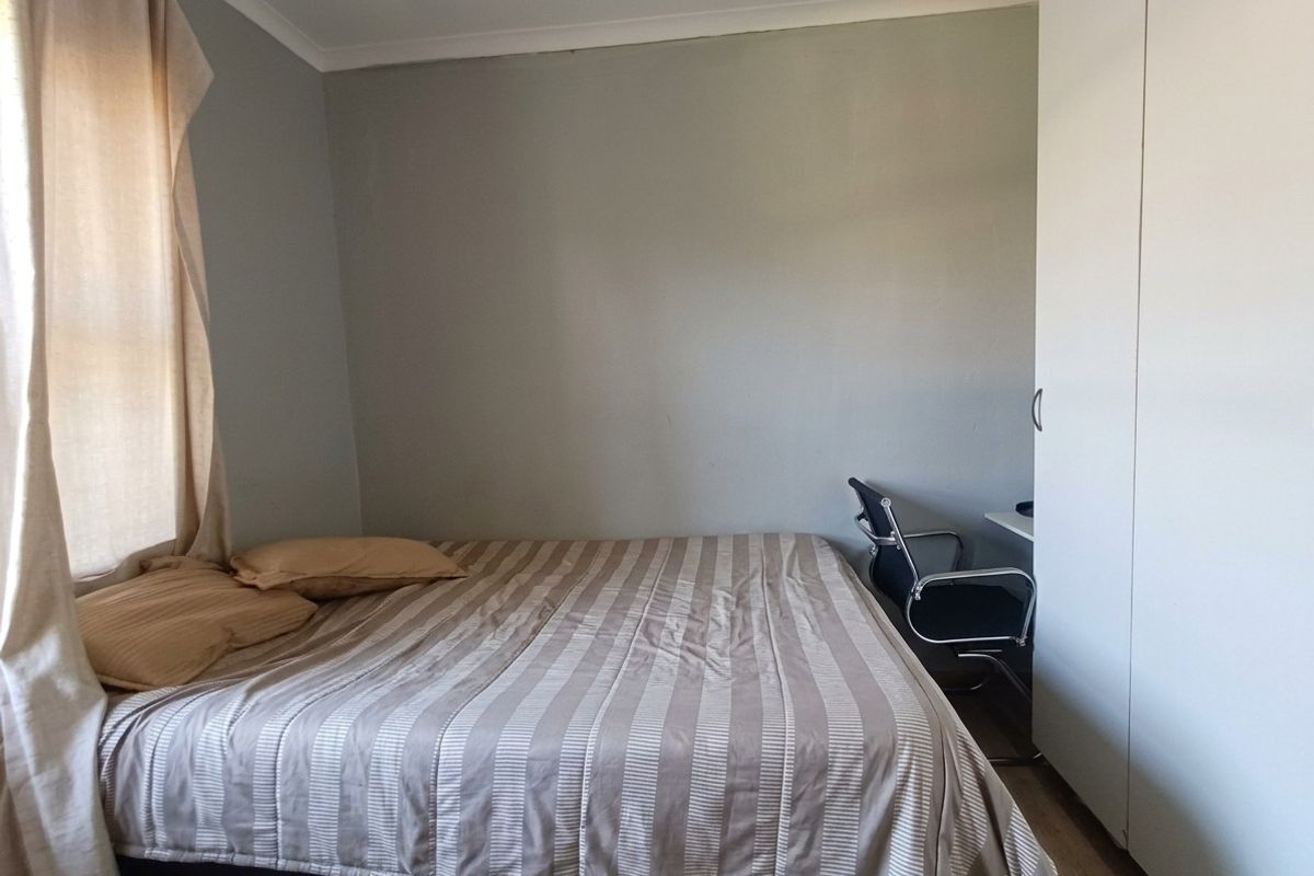 A functional bedroom featuring a built-in wardrobe and neutral wall finishes, providing a practical space for rest and storage.
