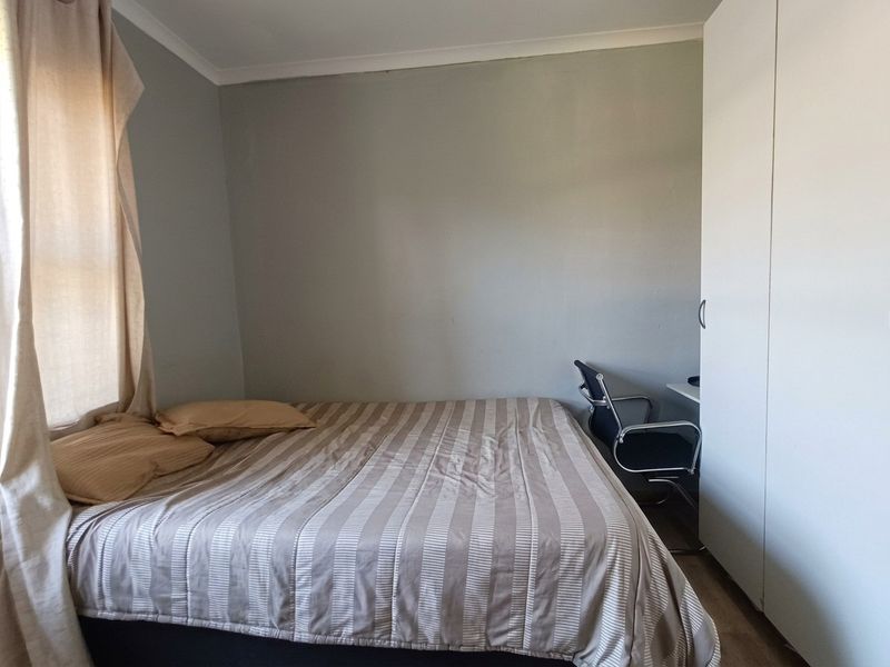 A functional bedroom featuring a built-in wardrobe and neutral wall finishes, providing a practical space for rest and storage.