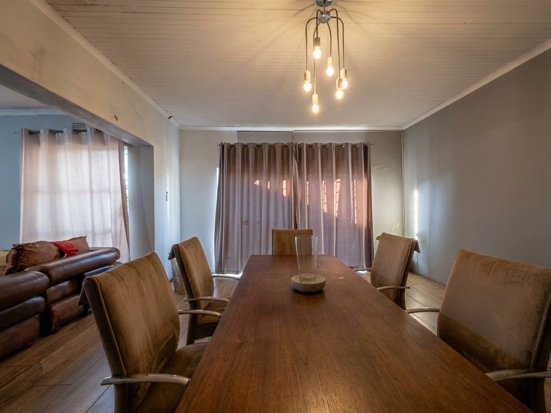 Dining area featuring timber flooring, tongue and groove ceiling, and modern pendant lighting, with an open-plan flow into the adjacent living space.