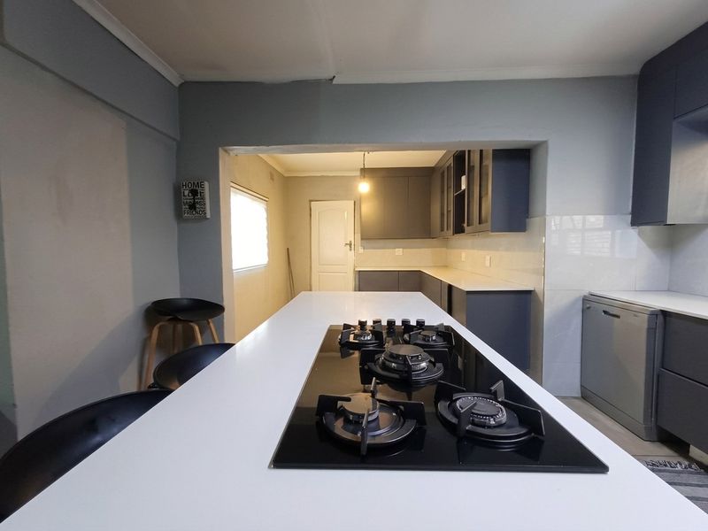 Modern kitchen featuring a central island with a built-in gas hob, ample cabinetry, and stone countertops, offering a functional and contemporary cooking space.